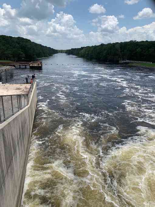 Churning water from the Rodman Reservoir enters the Ocklawaha River, where families fish from shore