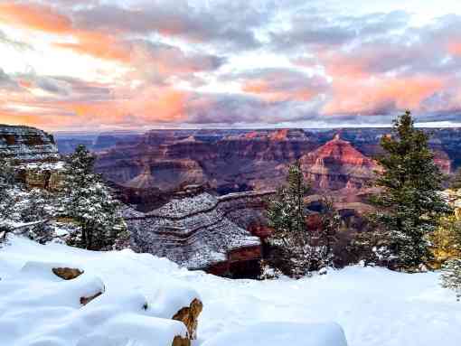 A pink sunset over the snow-covered rim of the Grand Canyon