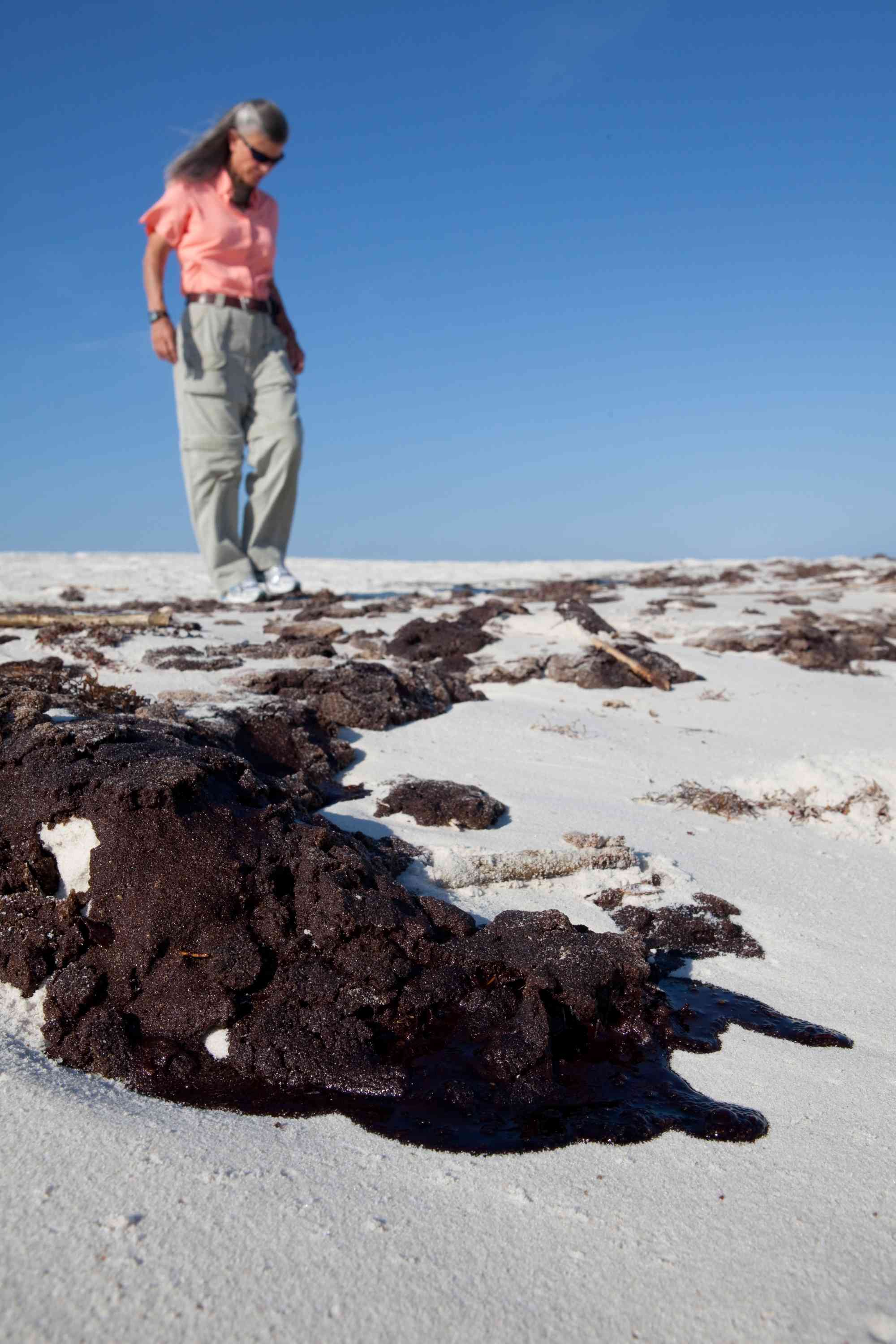 Jamie Rappaport Clark on the beach in the Gulf after the BP oil spill looking at washed up oil