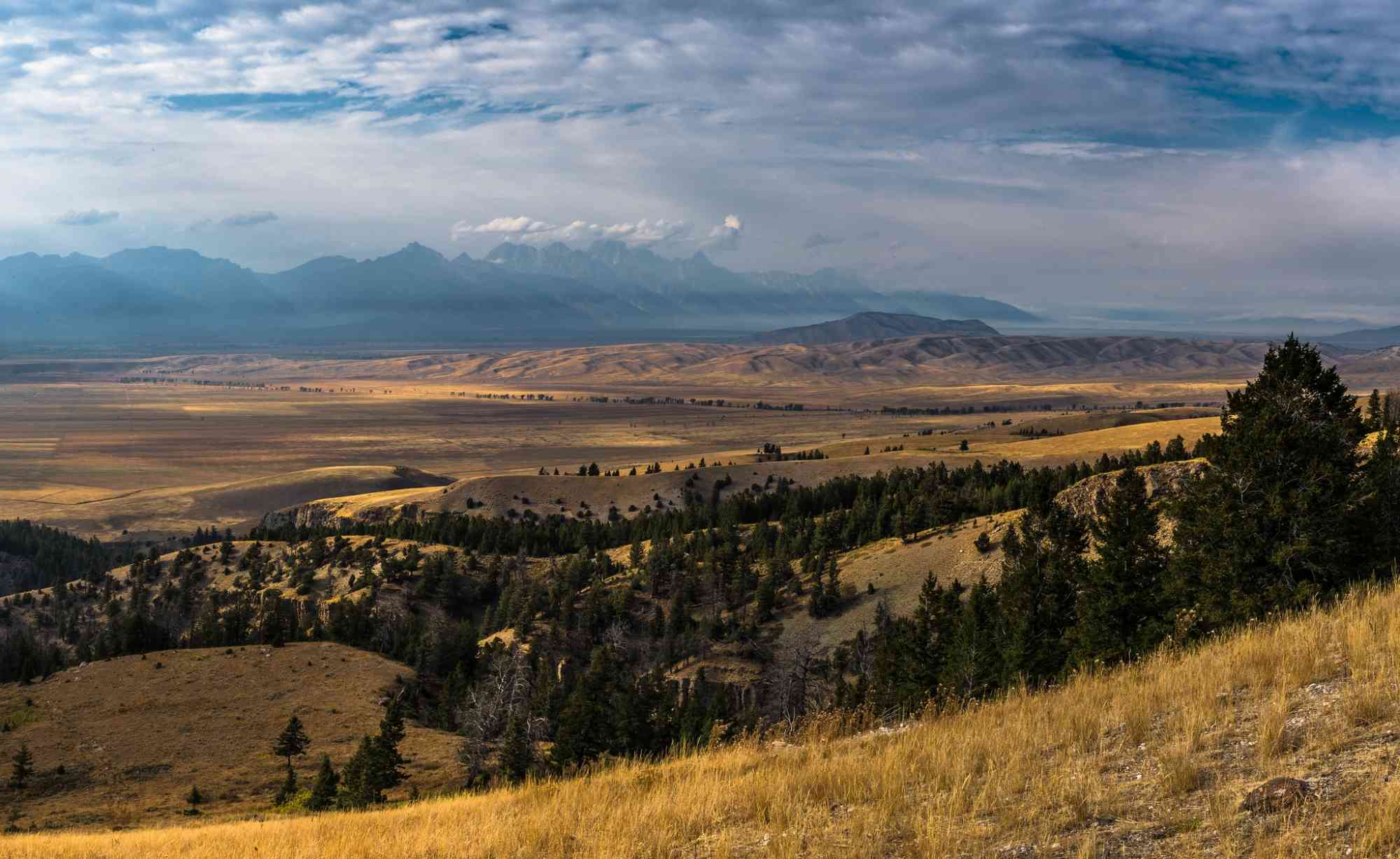 The Teton Range, partially obscured by smoke from the Berry Fire, rises beyond the Jackson Hole valley.