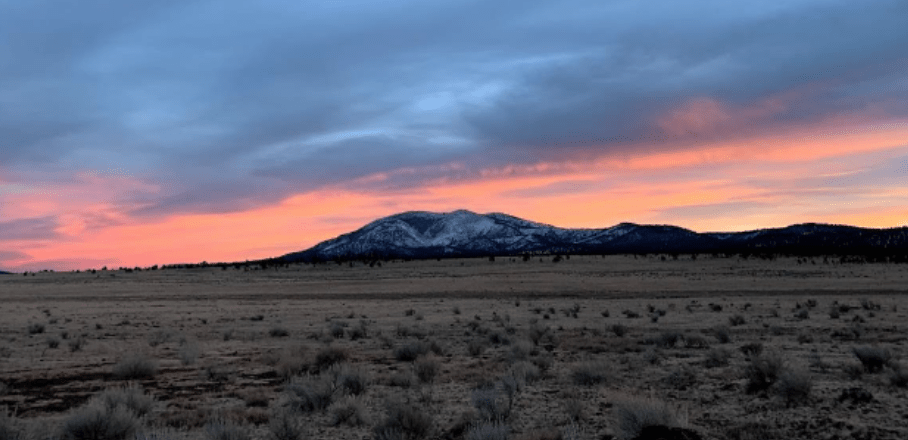 Sunset over the Elk Mountains in the distance from a desert landscape
