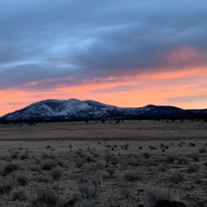 Sunset over the Elk Mountains in the distance from a desert landscape