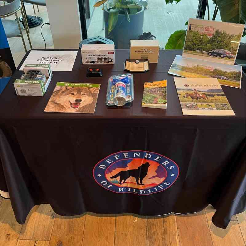 Several items are neatly laid on a table. The items are all tools and guides to help people minimize conflict with red wolves non-lethally. 